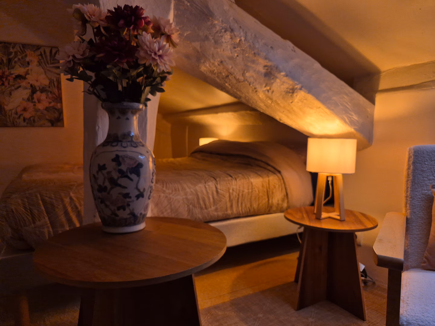 Une chambre sous les combles : lit fait, bouquet, lumière du soir