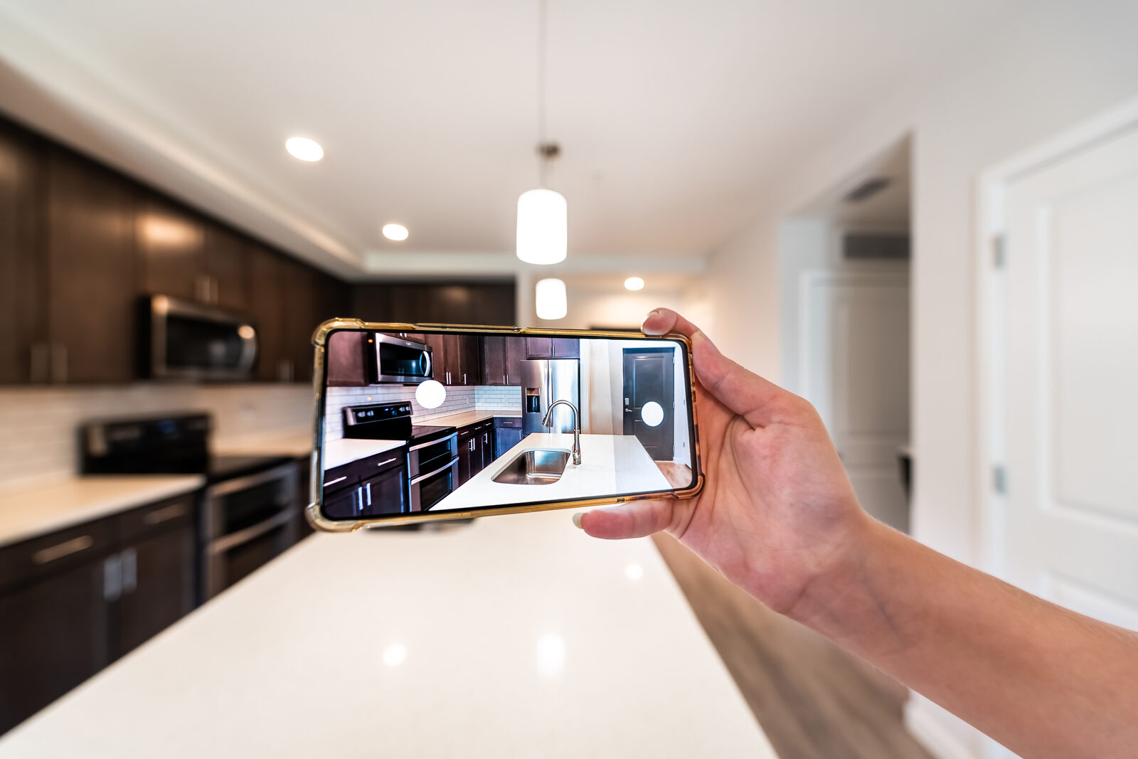 Une main photographie une cuisine avec un téléphone